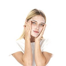 Frau mit Creme hält ihr Gesicht in den Händen